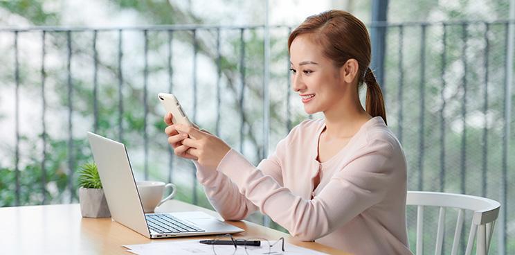A woman using her phone while holding a cup of coffee