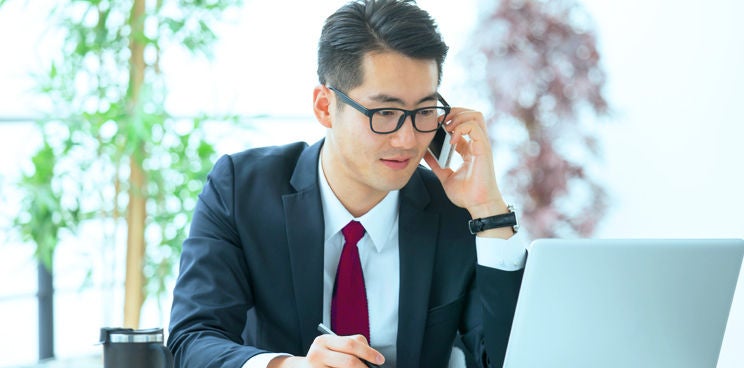 Man wearing a suit and glasses on his mobile phone.