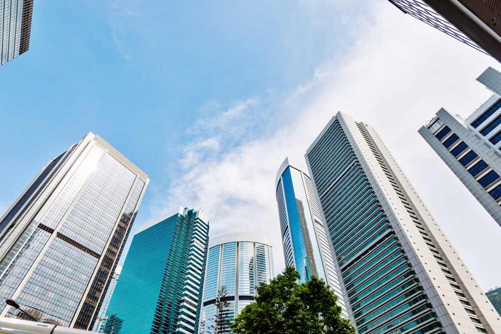 A woman looking ahead with tall office buildings in the background.
